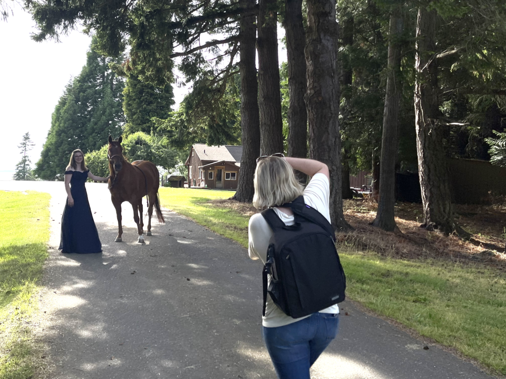 behind the scenes of photographer taking pictures of girl and her horse on a shaded driveway