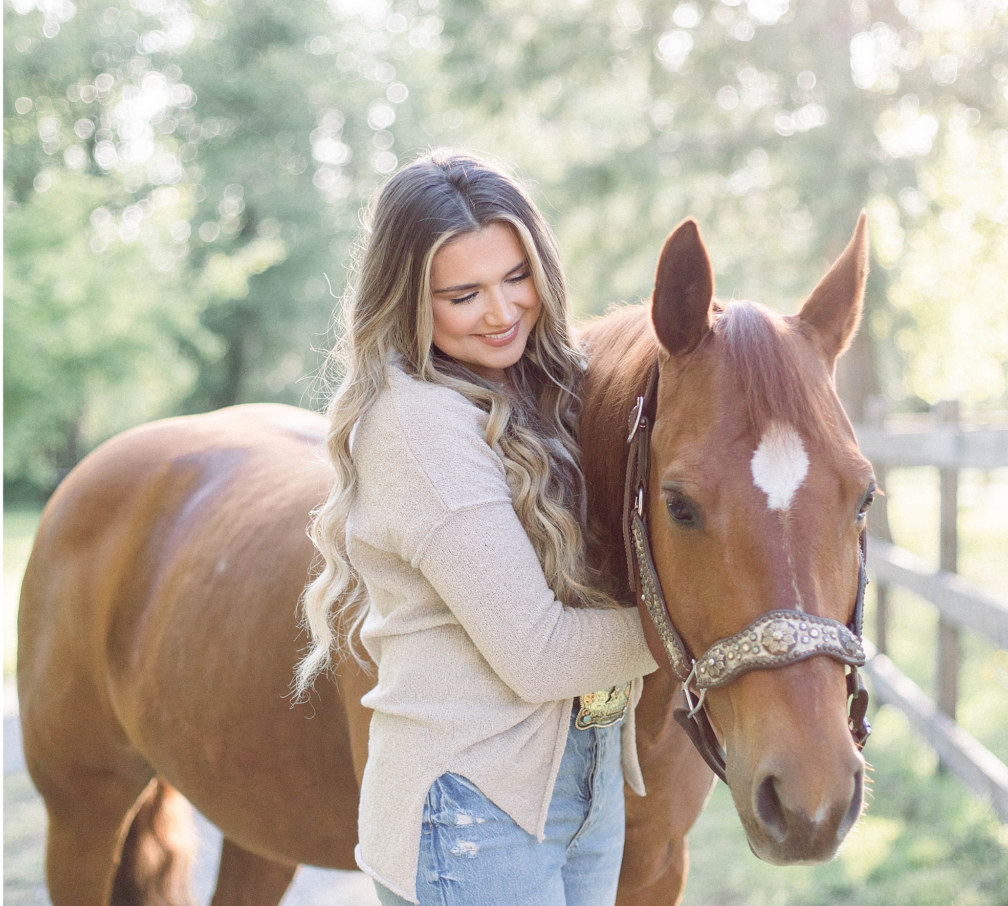 senior girl wearing beige sweater and jeans hugs her chestnut horse