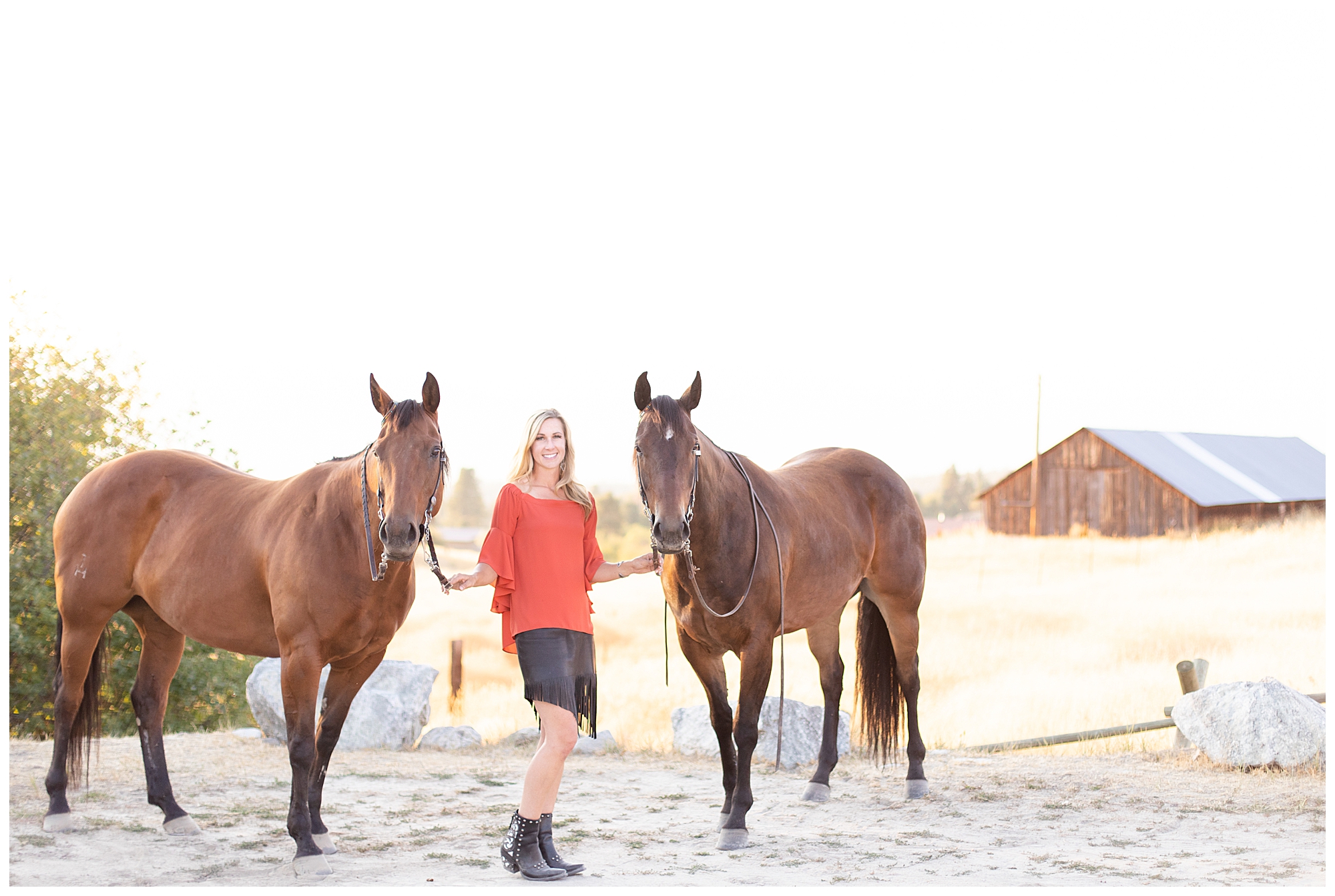 Woman wearing orange shirt and black skirt stands with her two horses at park in Corvallis Montana