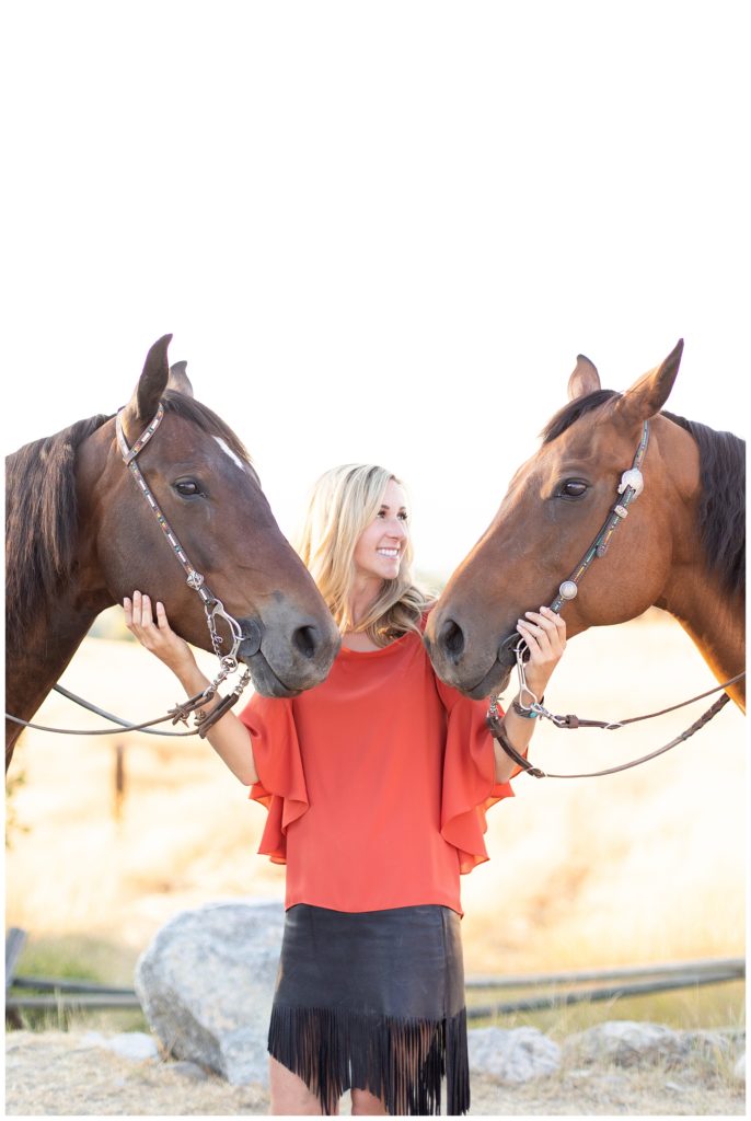 Woman standing with her two barrel racing horses wearing matching bridles 