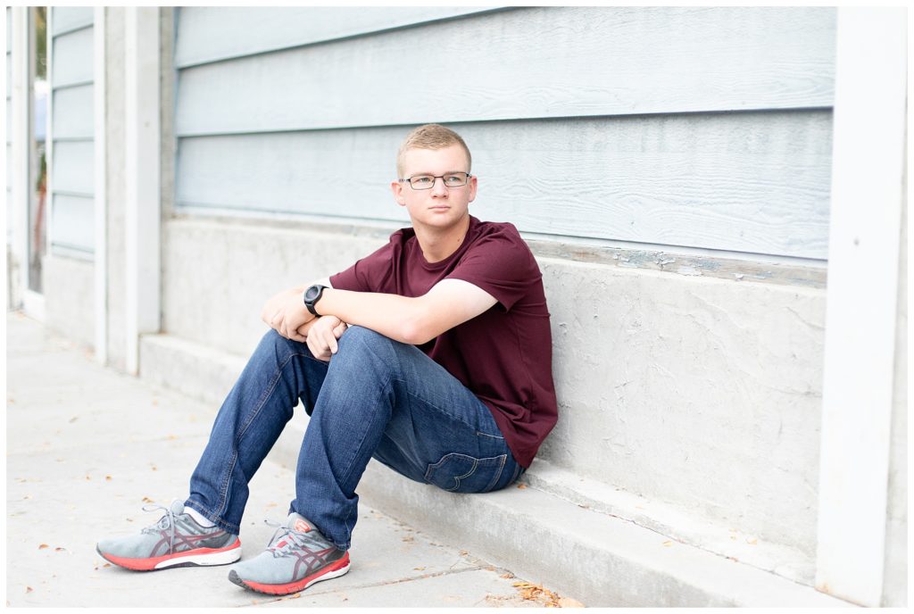 high school senior guy sitting in sidewalk in downtown Hamilton, Montana