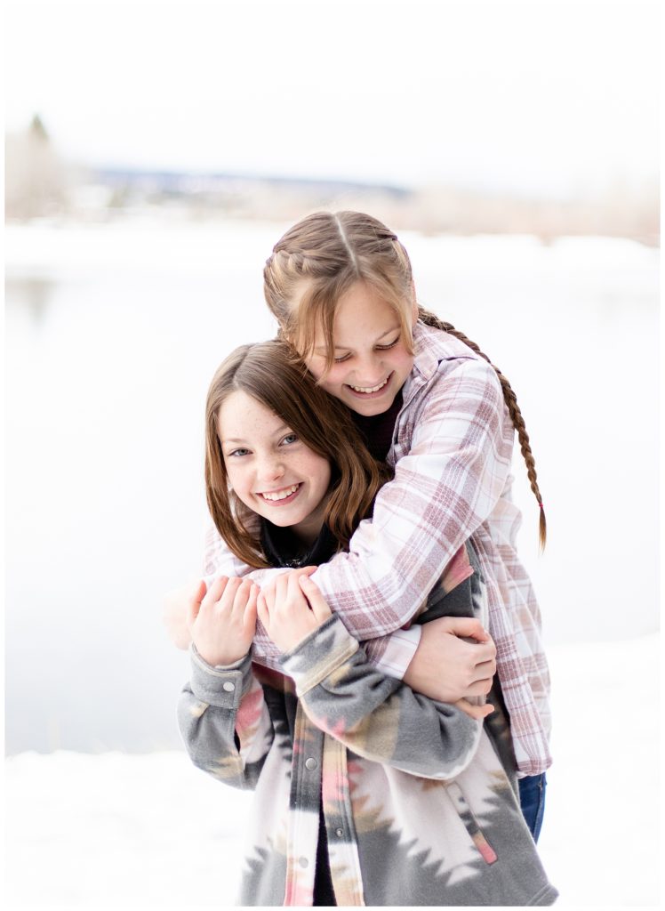 family photos in Corvallis, MT with Kat's Eye On Design Photography with sisters hugging in the snow
