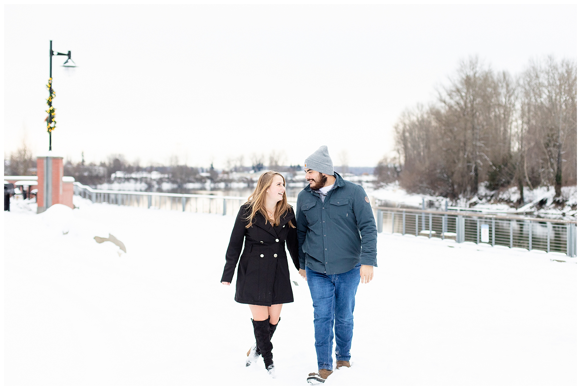 engagement photos in the snow with couple walking and smiling at each other