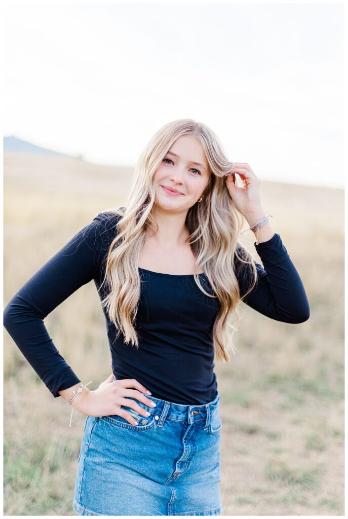 Knoxville senior photo of girl in field wearing black shirt and denim skirt