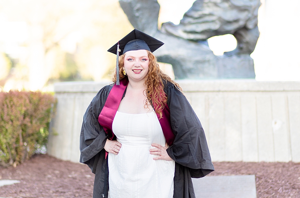 University of Montana senior wears cap & gown in front of Grizzly Bear statue for senior pictures with Missoula photographer Katherine Schot Photography
