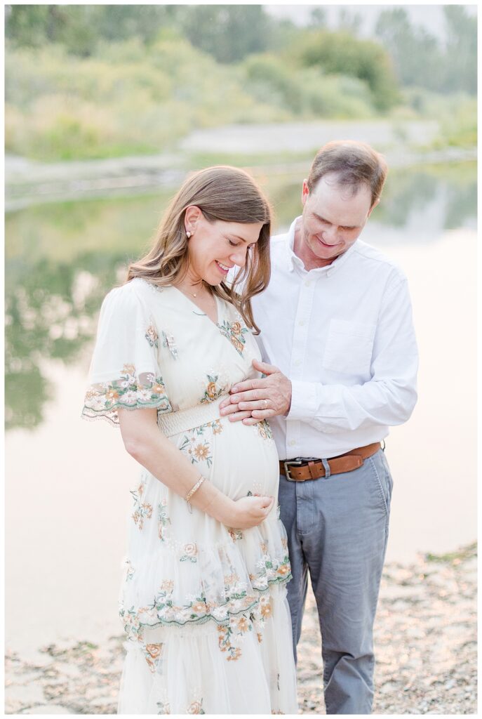 Missoula maternity photos of couple holding stomach smiling