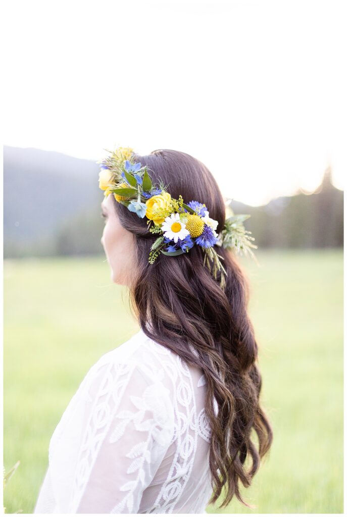 Elopement hair styling by Strands Salon with long curls under a flower crown of fresh florals in blue, yellow and white