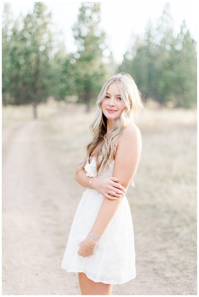 Missoula senior photos with senior girl standing in forest in white dress smiling